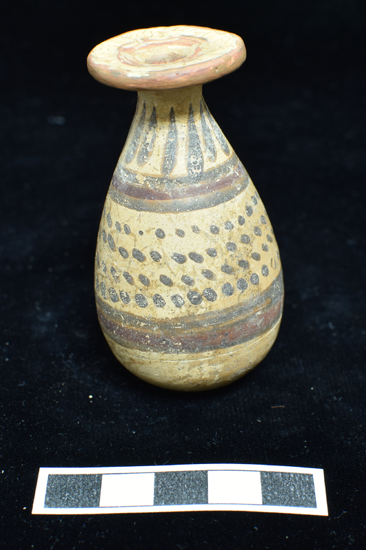 Small  alabastron w main zone of four h rows of dots banded by broad stripe above and below, w  narrow red stripe in center of each; pendant drops on shoulder; stripes around edge of rim and center aperture (possibly modern).