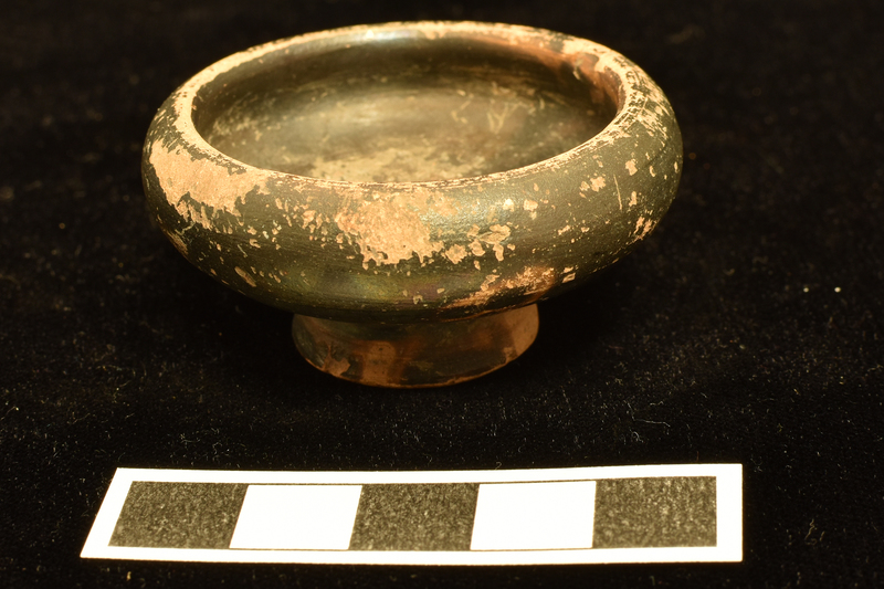 Bowl w almost straight sides flaring  fr high ring base, deeply conical on underside, to strongly incurving shoulder and  thick, plain edge.  Covered all over int and most of ext of ext w dark paint, some of which trickled onto underside of base.