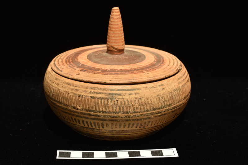 N.9a: Low shallowly convex body decorated, between bands of groups of 3 narrow stripes, w upper zone of multiple zig-zags, lower zone of short vertical stripes;  broad stripe at base.  Two pairs of suspension holes opposite one another on inner rim. N.9b: Fairly flat lid with tall conical handle; concentric stripes around surface of lid, narrow at edge; single broad stripe at center; and solidly coated at base of handle which is decorated with concentric narrow stripes.  2 pairs of suspension holes opposite one another near edge.