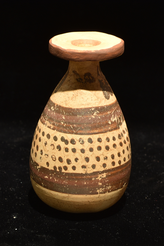Small alabastron decorated with main zone of four h rows of dots banded by broad stripe above and below, w narrow added red stripe in center of each; pendant drops on shoulder.