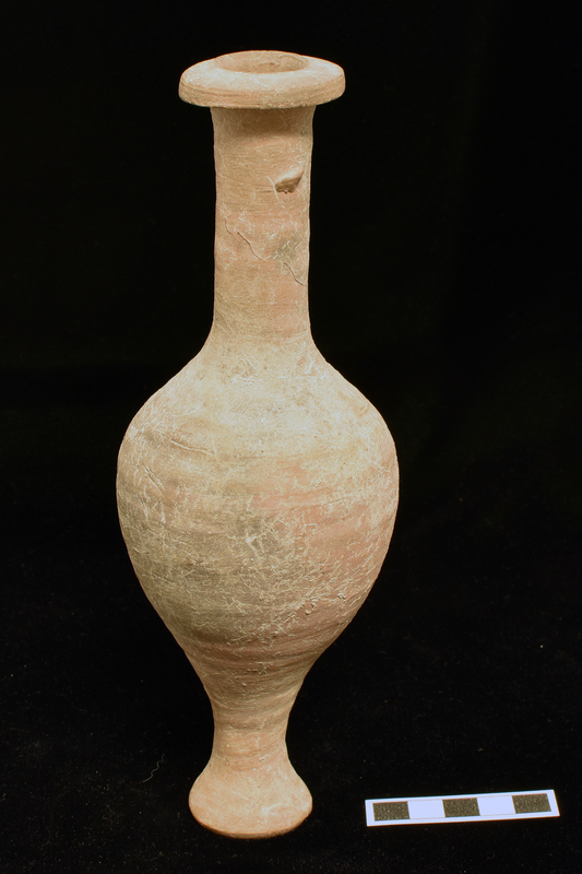 Bulbous body w max D ca mid-height continuing into tall concave pedestal flaring to flat bottom; tall cylindrical neck w projecting discoid rim shallowly convex on top.  Prominent wheel-marks approximating grooving all over ext.
