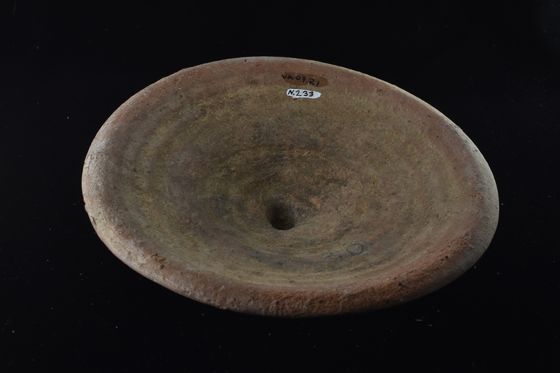 Convex lid with thickened edge and prominent wheel marks; in center of top a deformed short cylindrical handle which shows on surface striations of surface on which lid left to dry.