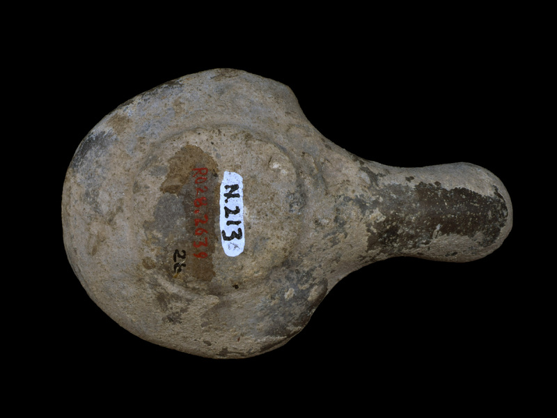Handleless, carinated reservoir on low raised base; large fill hole w torus moulding border from which lines radiate out to carination; large palmette from torus over nozzle surface; incipient lugs, with relief ?eyes at carination on either side of base of nozzle.  Probably originally painted all over ext.