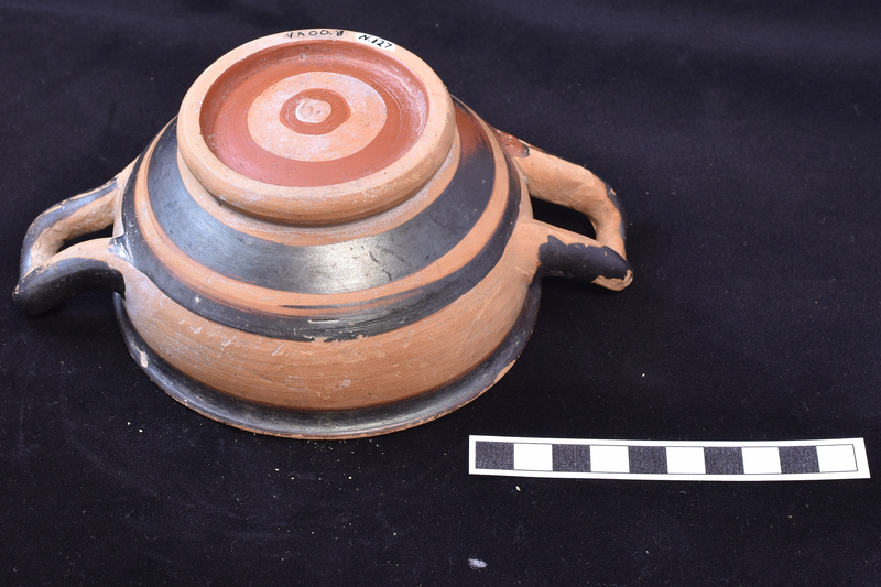 Rounded bowl on thick ring base with small out-turned rim handles of section varying from circular to elliptical attached at maximum diameter.  Interior completely coated except for reserved circle in base and reserved band at inner edge of rim; rim coated on top with continuation of paint to broad stripe at top of exterior; central section reserved except for exterior handles; below handles one narrow and one broad band; on under side of base inner side of base coated with paint extending on to base as broad stripe, small annulus of paint in center.