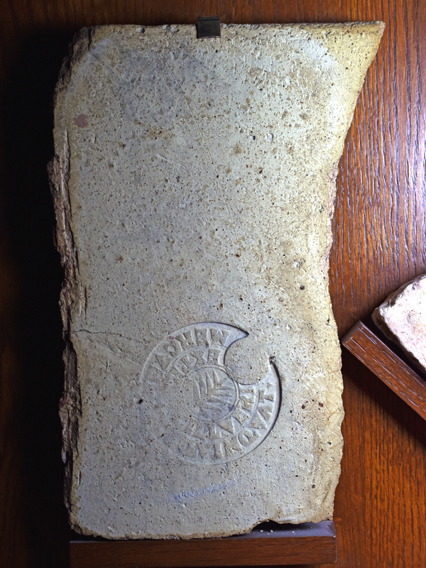 Stamped brick from Italy (1st half of 2nd c CE). Originally square fragment (see Lind pl. 49J), now broken in half. Large circular stamp with small palm branch in the center; around it are two rows of quadrate letters.