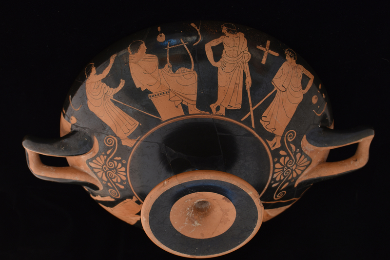 Kylix by Sabouroff Ptr, v. Oakley letter in file.  Decorated w scenes fr palaestra w  palmettes under handles; interior of handles & adjacent body, edge of foot & int of stem reserved. Tondo defined by discontinuous maeander w reserved exerque: Youth at l seated on altar facing r, swathed in himation which pulled over head on which added red fillet; at r standing youth in 3/4 view fr rear, r hand on hip, leans toward first, resting on smooth staff under l arm; wreath in added red.  Side A: Presentation of fillet to lyre-player; fr l to r: youth w fillet in added red in himation leaning r w staff under l arm & holding fillet in added red toward lyre-player swathed in himation, who sits on altar facing r holding lyre upright and wreath in added red; to r of lyre player frontal youth in himation pulled over l shoulder leaving chest bare,  r arm bent w hand on hip and w staff under l arm, face in profile to l, wreath in added red, feet crossed at ankles; at l another youth in himation, 3/4 view fr back, leaning in on staff under l arm  toward center, w r arm bent & hand on hip, face in profile to l w wreath roughly incised, possible modern;  on background aryballoi, strigils and one wooden cross; K A L O S in added red between figures 1 and 4.  Side B: Four youths in conversation fr l to r: frontal youth holding staff w curved top in r hand, r arm bent under himation, face in profile to r, wreath in added red; youth swathed in himation seated on altar facing r w arms bent holding bent r knee, all under himation; youth in 3/4 view fr rear leaning l w arm bent & hand on hip, leaning on staff under l arm, face in profile to l, fillet in added red; frontal youth with arms swathed in himation, r raised, left bent to hip, face in profile to l; on backgrd aryballoi, flute cases, strigils.