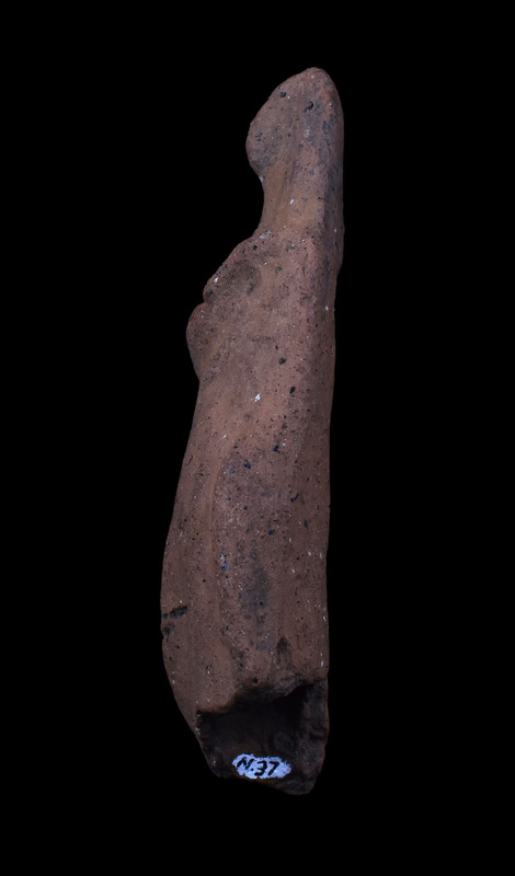 Mouldmade standing figure w palla draped over head and falling on either side, pulled across body diagonally over r arm; l arm at side holding vertical clump of drapery; slightly projecting right knee.  Pinched ridge of clay articulating face.  2 large vent holes in back.