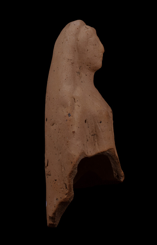 Mouldmade standing figure w himation draped over head and falling down over outside of r arm, coming forward over l breast, w fold coming across fr r side and tucked under l arm folds of chiton and himation articulated by incision.  Hairline, eyes, nose, and mouth articulated by incision.