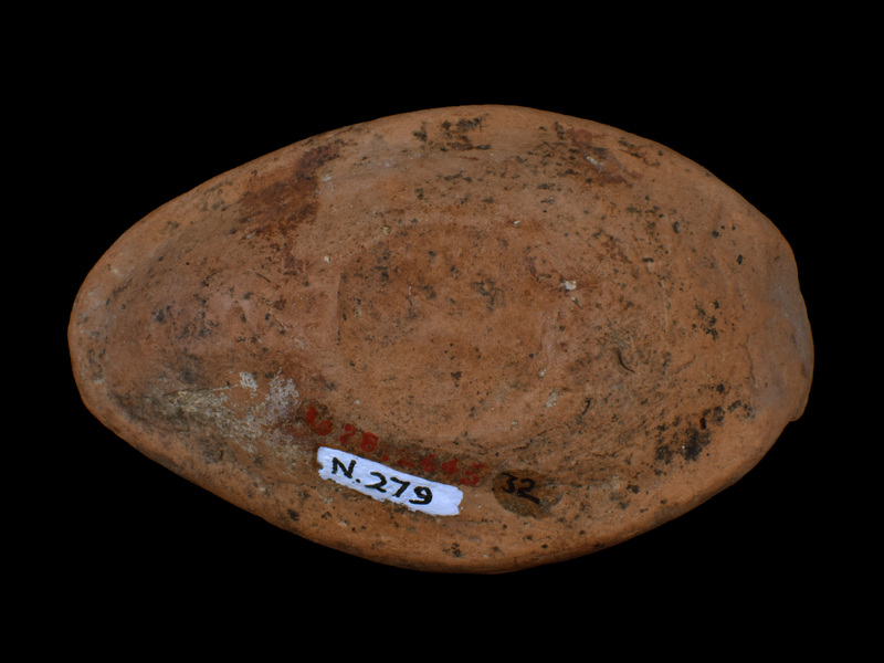 Slipper lamp w upturned solid rectangular lug handle, edges of which defined by relief band within which relief X below, relief ?rosette above.  Carinated reservoir w flattened carination, large fill hole surrounded by two relief bands;  on upper surface decoration of open V's pointing toward carination within and between which relief dots; relief Greek cross on nozzle.  Ca flat base depressed within poorly articulated raised band; possible mark at edge of band two indistinct depressions.  Top surface coated w red paint, some of which dripped to underside; blackened nozzle.