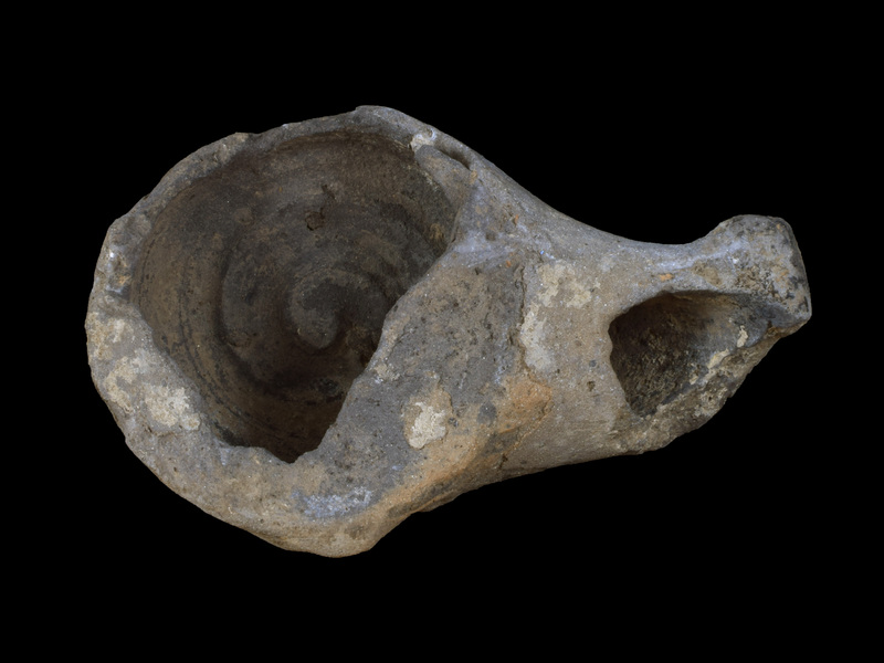 Tall, straight-sided reservoir w short bevel to ca. flat base; traces of small, un-pierced lug on edge of body wall and top surface which, as pres., plain & concave; broad, spathate nozzle.  No evidence of paint.