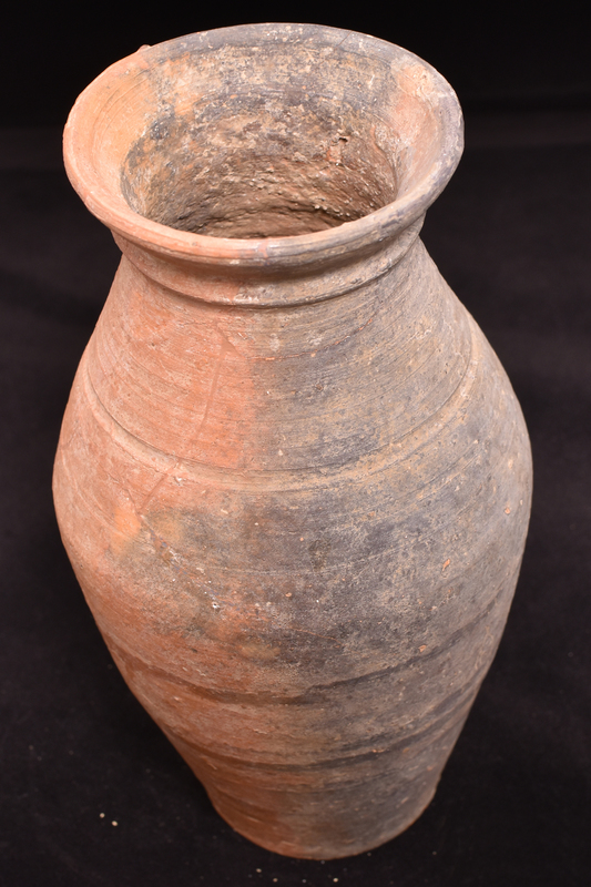 Tall body w slight carination ca mid-height on flat base w tall flaring rim concave on int; traces of handle just above max D & at base of rim; prominent wheelmarks all over.   H rib at base of rim; incised groove at base of shoulder.