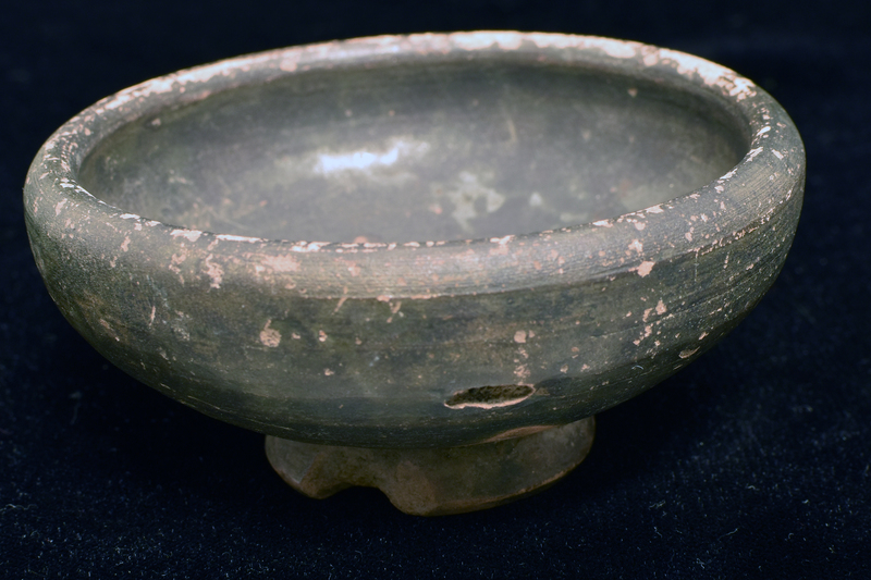 Bowl w spreading convex walls curving in to thick plain rim; ring base w deep conical underside w nippled center.  Coated all over int and most of ext w dark paint which dribbled onto lower walls of  underside of base.