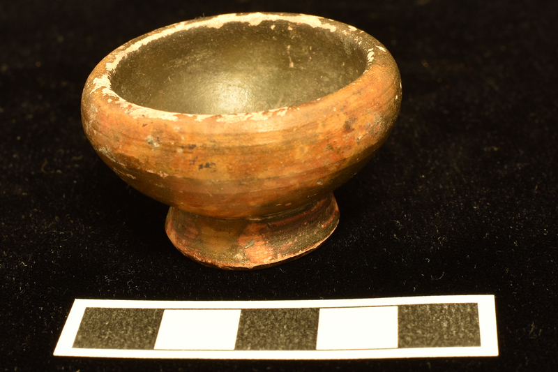 Bowl w convex sides curving in to thick plain rim, pedestal base, deeply conical on underside.  Int & ext and most of underside of base coated w dark paint.