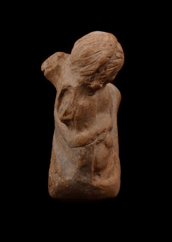 On rectangular base chubby Eros reclining on right elbow with right hand on rabbit.  Round face with eyebrows, eyes, nostrils, mouth, and cleft in chin articulated by incision; wreath on head with hair articulated by incisions going from forehead down back of head on either side of wreath, with clumps of hair articulated by irregular incision falling on either side of head.  Left arm covered by drapery stretched out and resting on bent left leg; incised lines roughly articulating folds of drapery; some articulation of feathers of left wing.  Raised band runs around back of figure under back of wings, possibly meant as drapery.