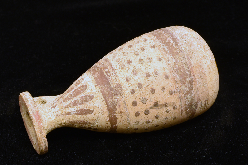 Piriform body w slightly flattened base w central sharp-edged circular depression; flat rim and v handle of plano-convex section from top of neck to underside of rim.  Decorated in dull red paint: stripe around outer half & edge of rim, elongated pendant drops on neck, 5 irregular rows of dots on body between two broad h stripes.