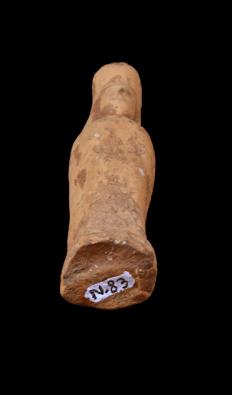 Mouldmade standing female of Dadaelic type with tall polos. Bilaterally symmetrical with arms close to sides, probably wearing simple tunic belted at waist. Triangular contour of face, nose articulated with slight depressions for eyes on either side; some indication of mass of hair straight across forehead. Stands on squarish base, articulated primarily at front.